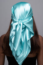 Load image into Gallery viewer, Slender black woman with straight brown hair below her shoulders wearing a light blue, shiny scarf tied in a knot behind her head.
