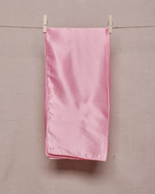 Load image into Gallery viewer, Rectangular, folded, baby pink satin scarf held on a clothesline by two clothespins in front of a light beige background
