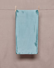 Load image into Gallery viewer, Rectangular, folded, light blue satin scarf held on a clothesline by two clothespins in front of a light beige background
