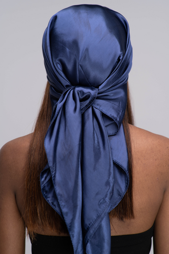Slender black woman in a black tube top with straight brown hair below her shoulders wearing a shiny, navy blue scarf tied in a knot behind her head.