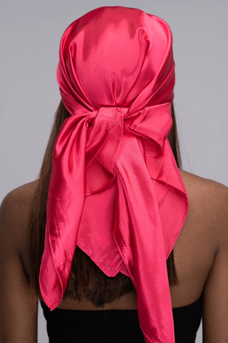 Slender black woman in a black tube top with straight brown hair below her shoulders wearing a shiny, bright pink scarf tied in a knot behind her head.