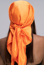 Load image into Gallery viewer, Slender black woman in a black tube top with straight brown hair below her shoulders wearing a shiny, bright orange scarf tied in a knot behind her head.
