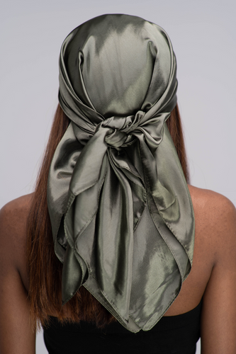 Slender black woman in a black tube top with straight brown hair below her shoulders wearing a shiny, khaki green scarf tied in a knot behind her head.